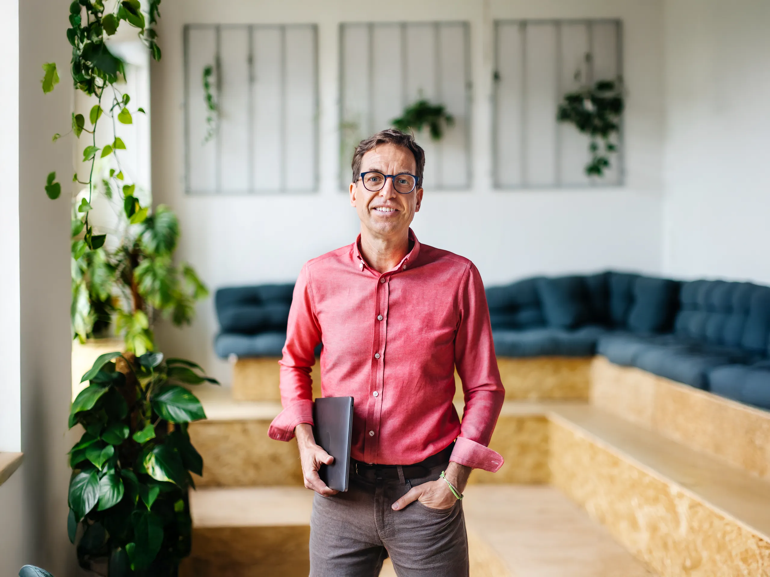 Geschäftsmann mit Tablet steht in modernem Büro mit Pflanzen