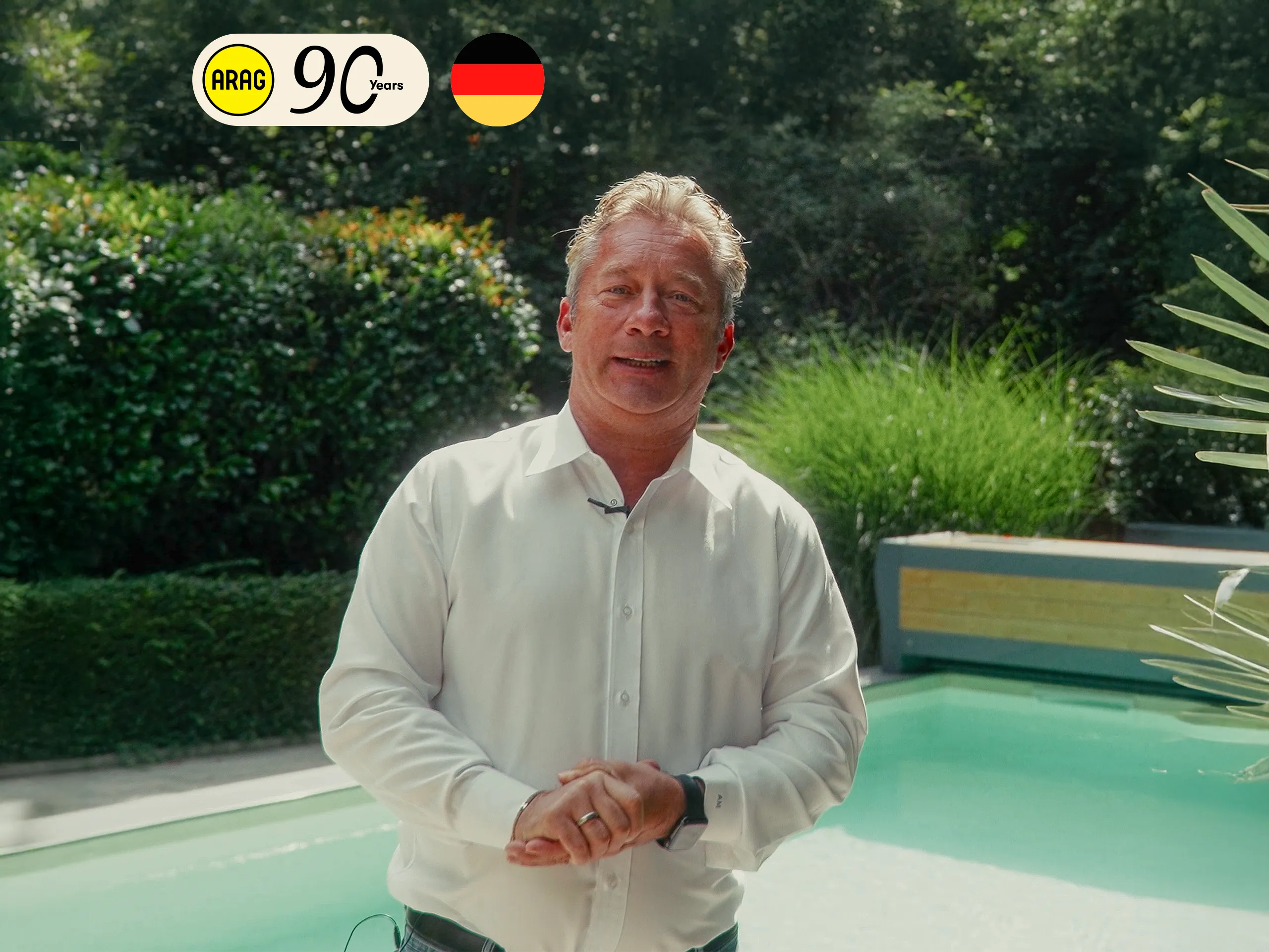 Immobilienkaufmann Andreas steht im Garten vor seinem Pool