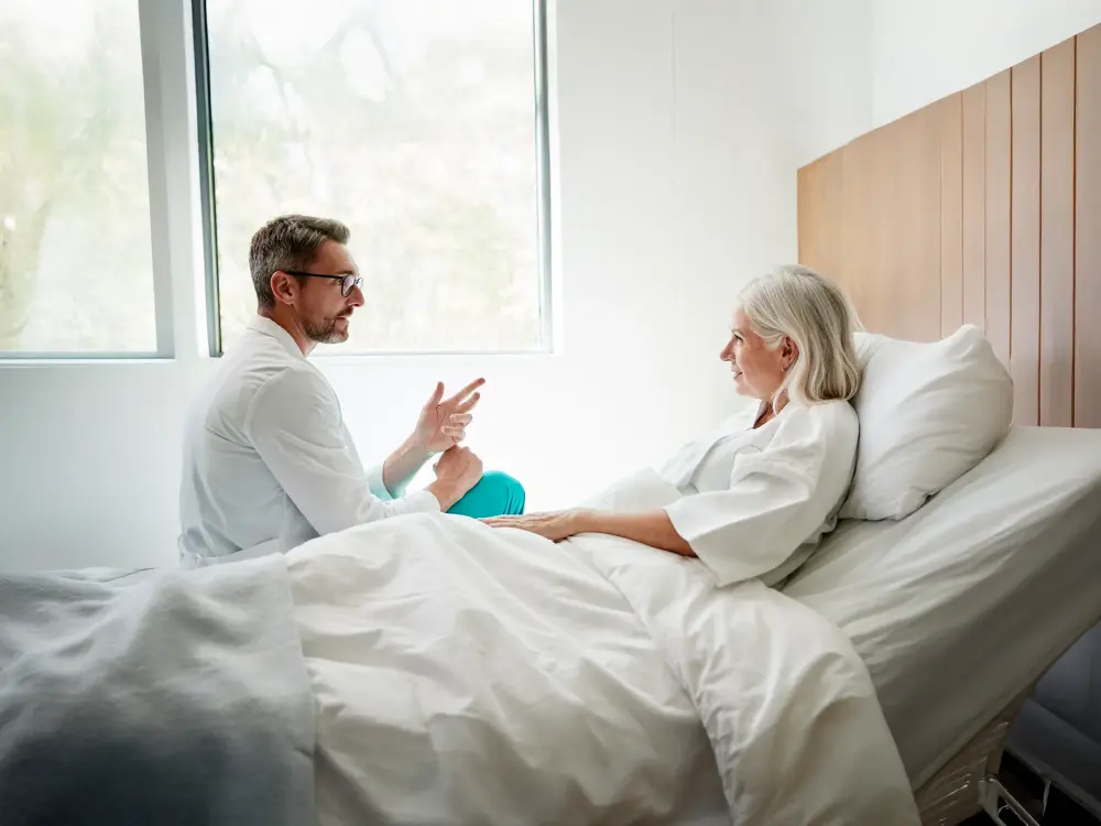 Arztgespräch mit älterer Patientin im Krankenhausbett