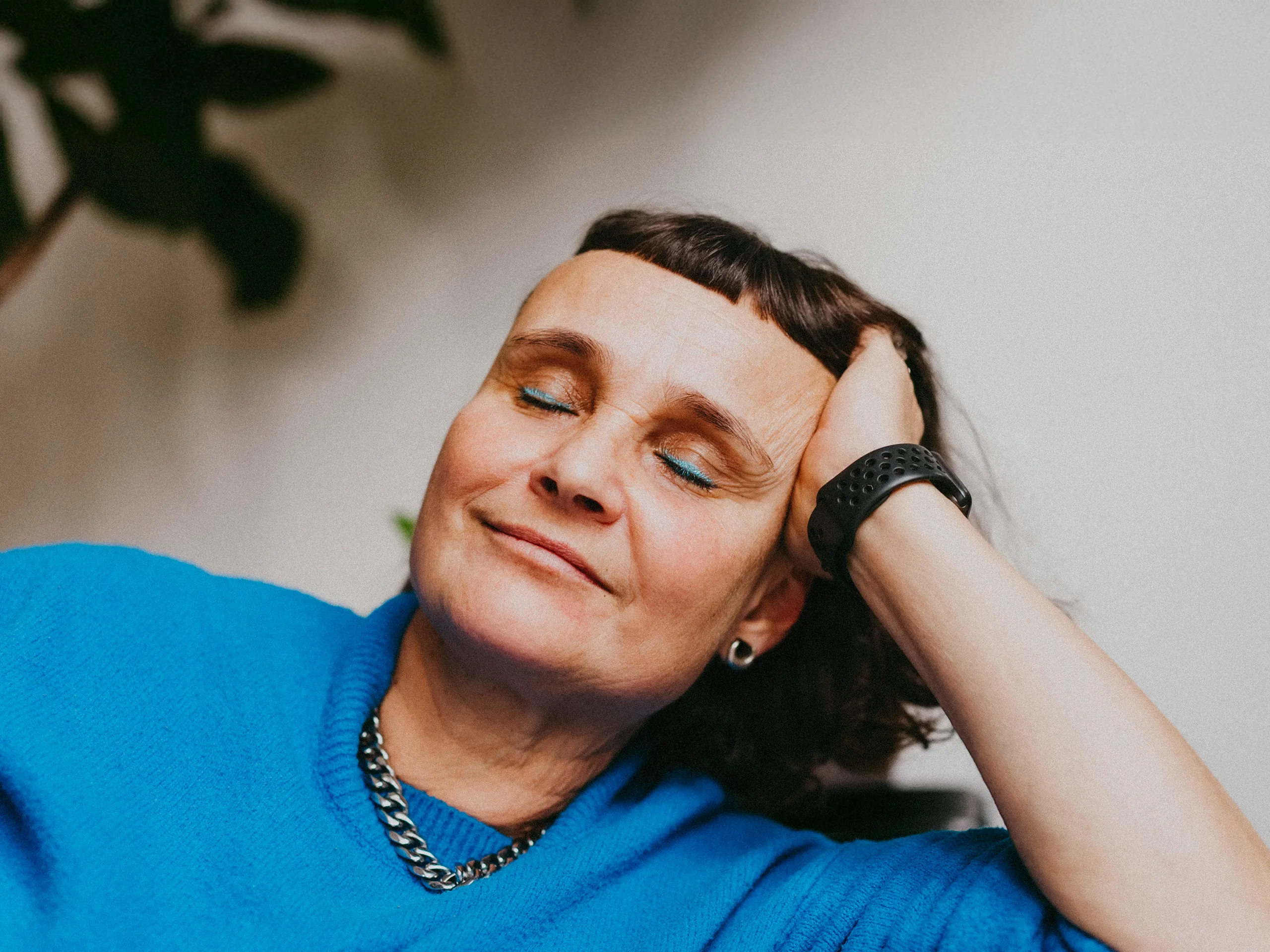 Frau mit blauem Lidschatten lehnt sich entspannt zurück