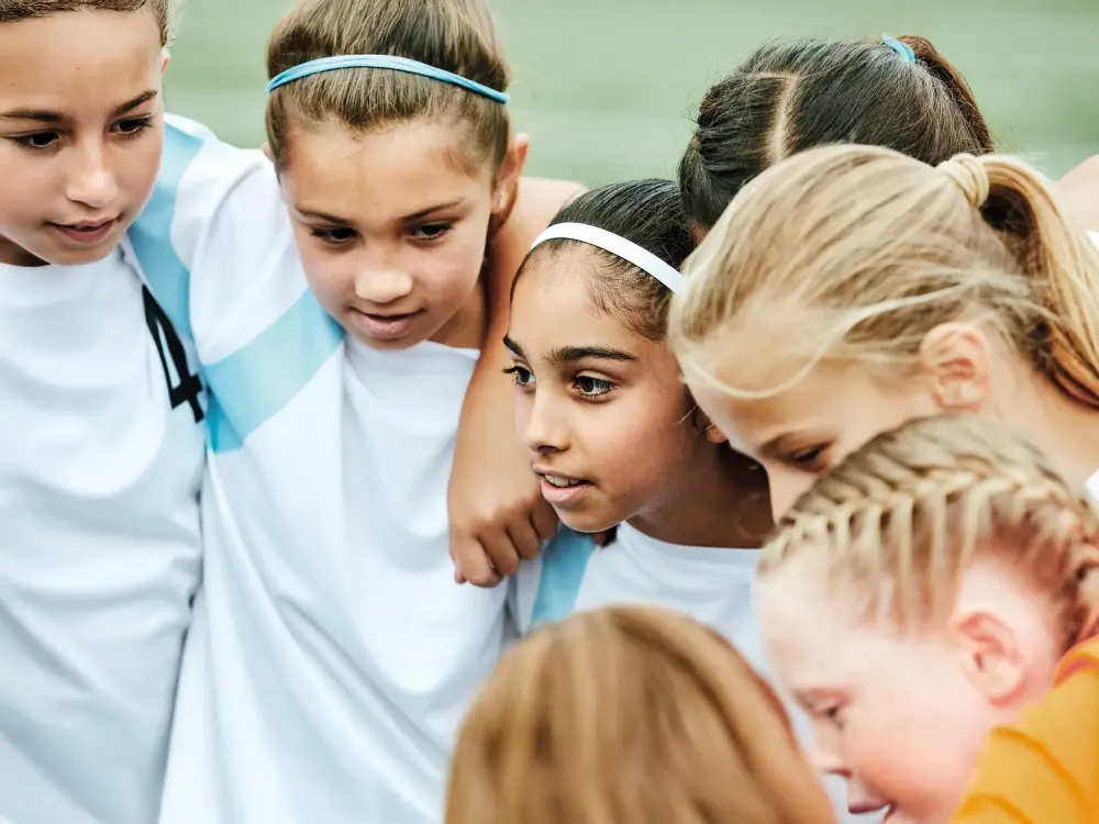 Mädchen-Fußballteam steht im Kreis für Teambesprechung