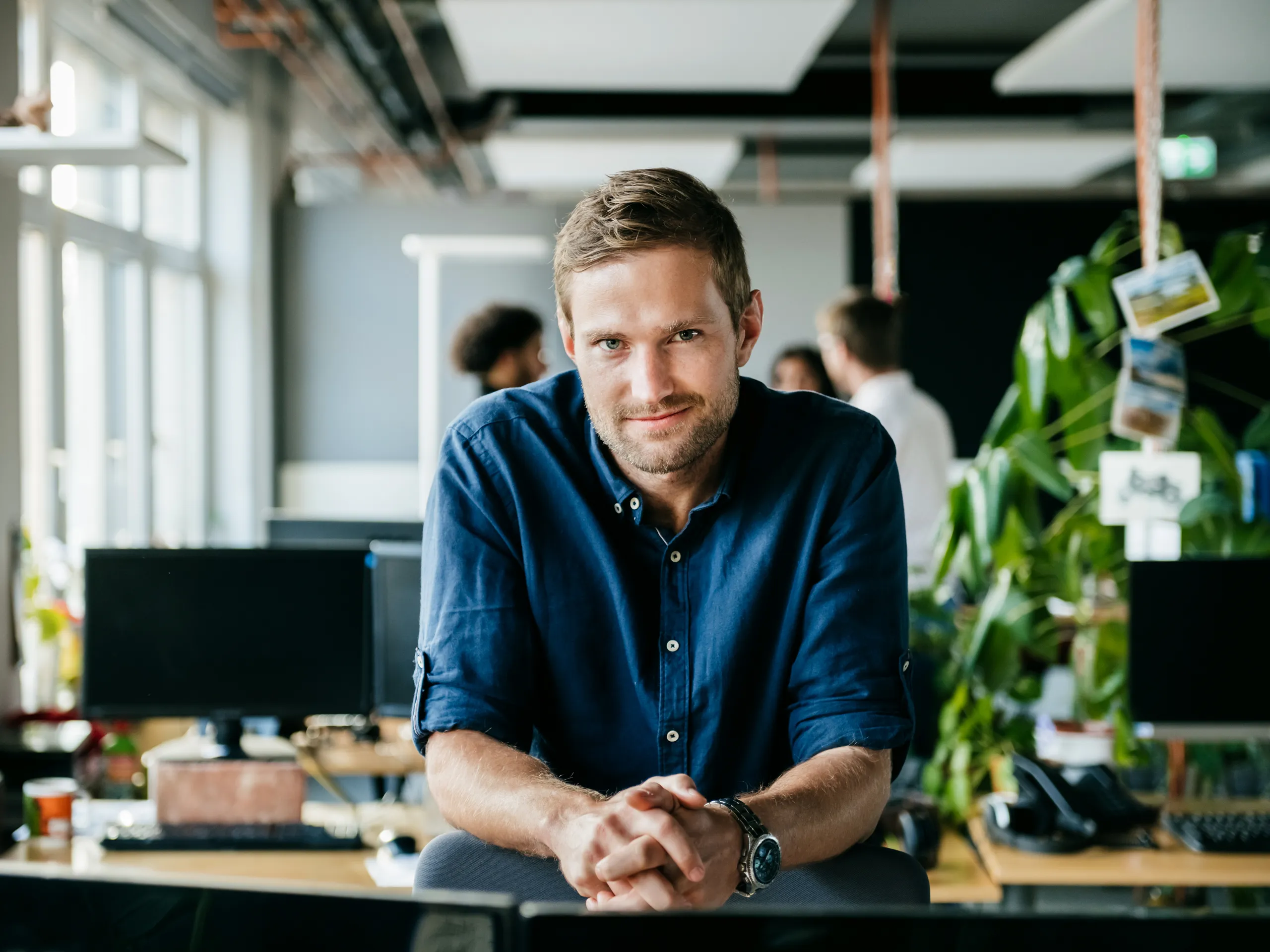 Mann in blauem Hemd sitzt an einem Schreibtisch in einem Büro